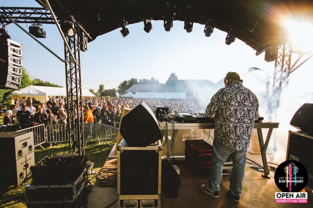 Vue impressionnante depuis la scène avec DJ HS mixant face à une foule de festivaliers enthousiastes.