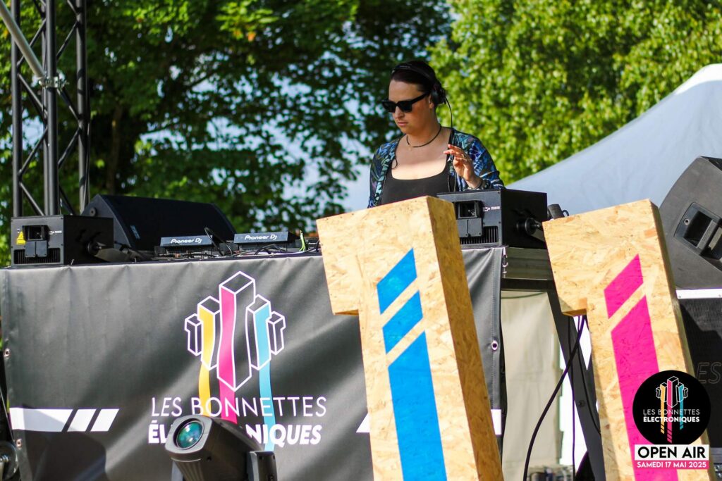 La DJ JUSTINE en pleine performance derrière les platines lors du festival Les Bonnettes Électroniques.