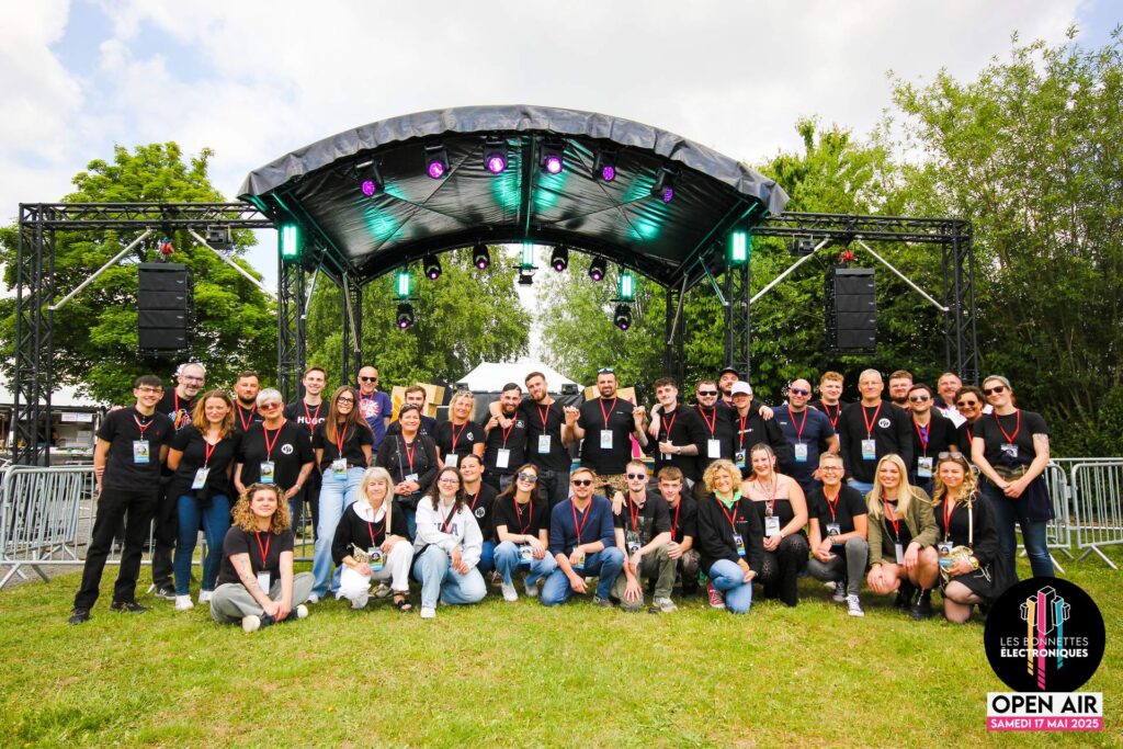L'équipe complète des bénévoles et le staff du festival Les Bonnettes Électroniques 2026 réunis devant la scène à Étaing.